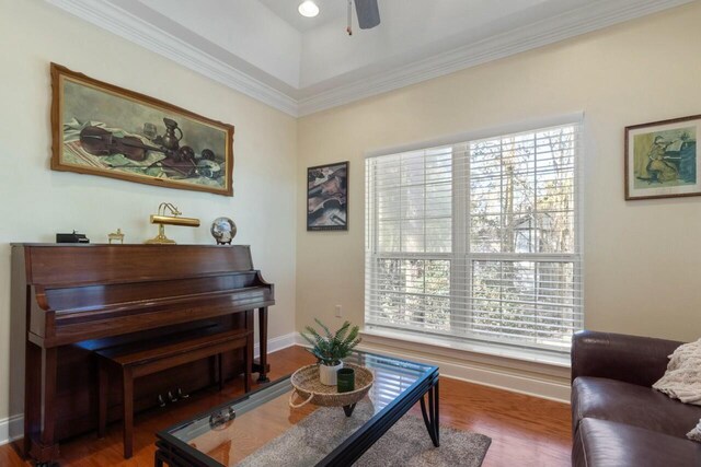 living area featuring ceiling fan, baseboards, wood finished floors, and crown molding