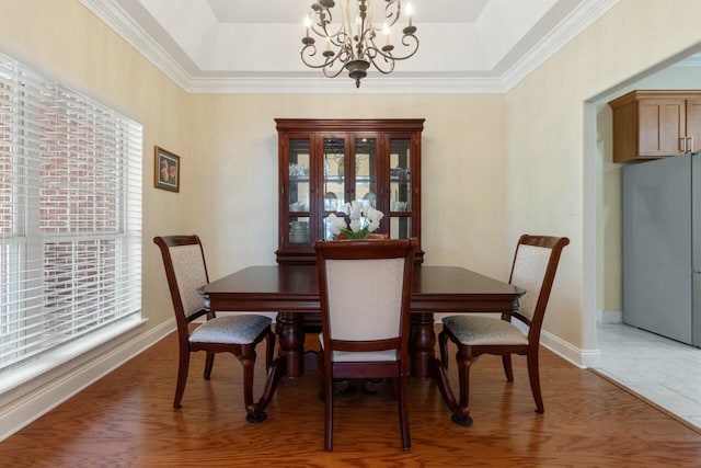 dining room featuring baseboards, a raised ceiling, and a chandelier