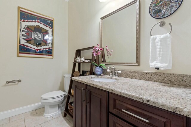 bathroom featuring baseboards, toilet, vanity, and tile patterned flooring