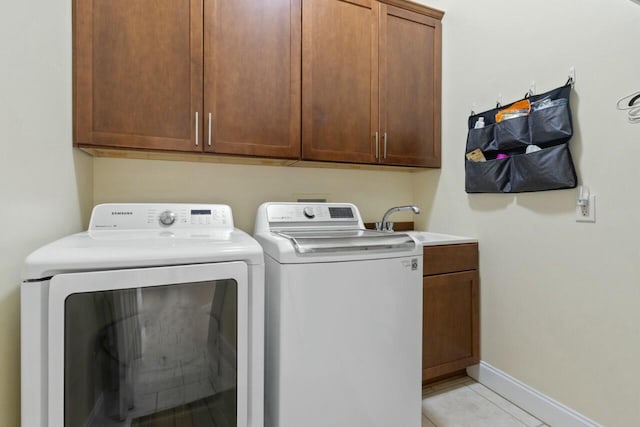 laundry area with cabinet space, separate washer and dryer, baseboards, and a sink