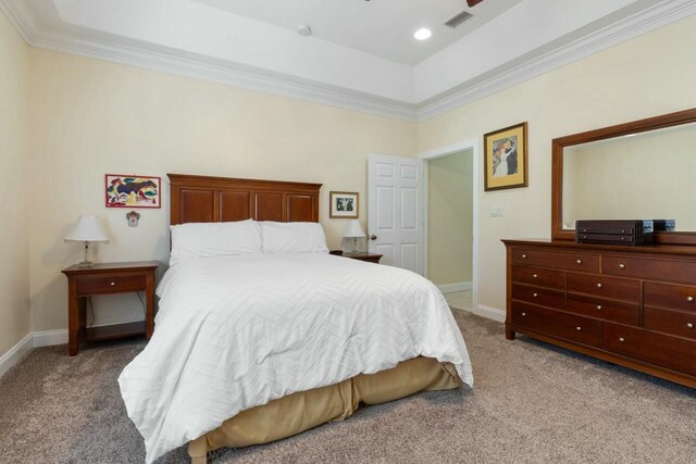 carpeted bedroom featuring visible vents, baseboards, and ornamental molding