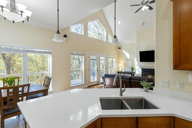 kitchen featuring open floor plan, french doors, brown cabinetry, a glass covered fireplace, and a sink