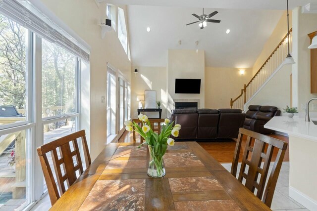 dining area with a ceiling fan, recessed lighting, a fireplace, a towering ceiling, and stairs