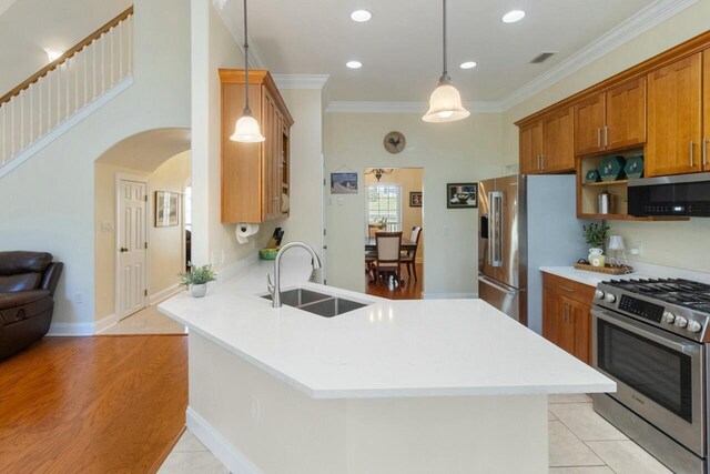 kitchen with brown cabinetry, a peninsula, a sink, ornamental molding, and stainless steel appliances