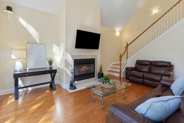 living room with stairway, baseboards, wood finished floors, and a tile fireplace