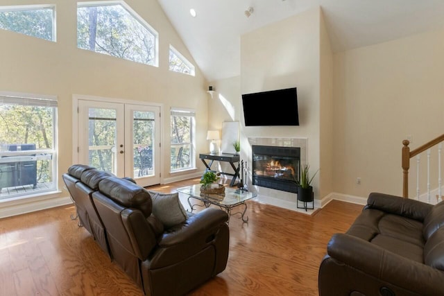 living room featuring a tiled fireplace, stairs, wood finished floors, and a wealth of natural light