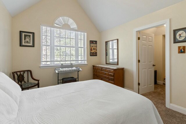 bedroom with vaulted ceiling, baseboards, and carpet floors