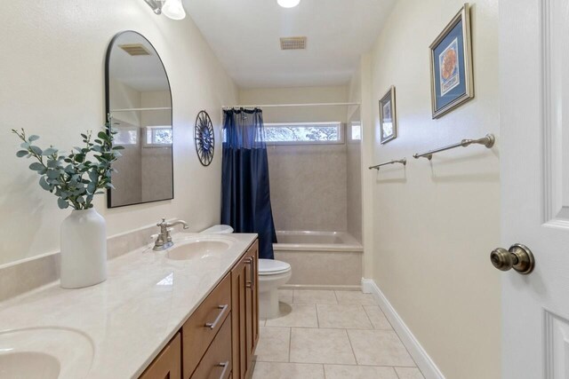 bathroom featuring visible vents, double vanity, a sink, tile patterned floors, and toilet