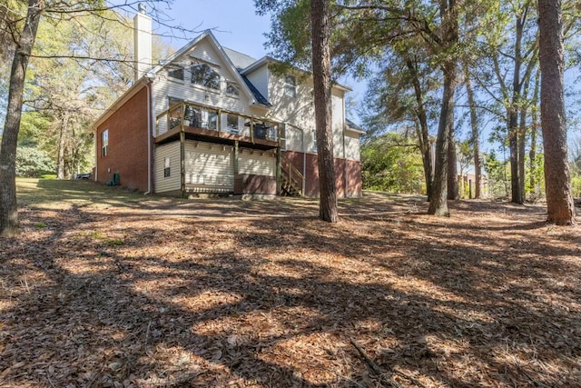 back of house with brick siding and a chimney