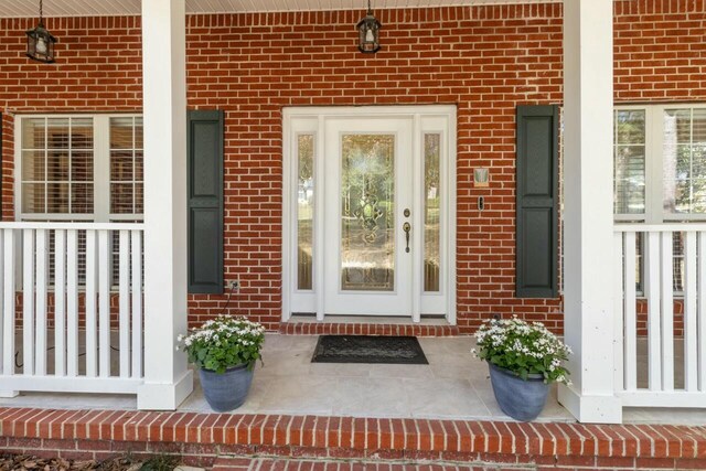 property entrance featuring brick siding and a porch