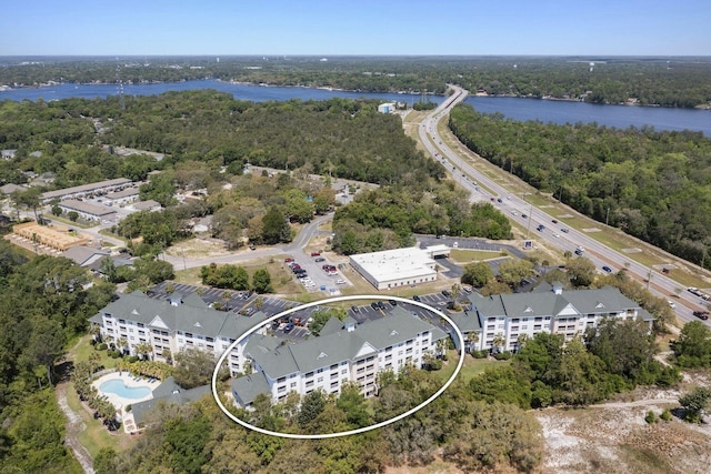 drone / aerial view with a wooded view and a water view