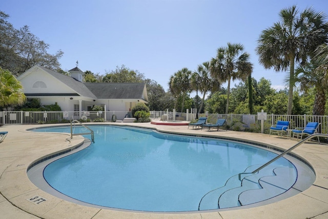 community pool with a patio and fence