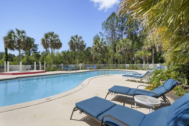 community pool with a patio area and fence