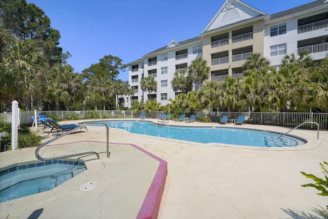 community pool featuring a patio area, a hot tub, and fence