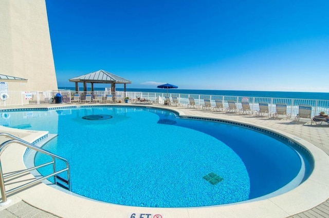 community pool featuring a gazebo, fence, a water view, and a patio