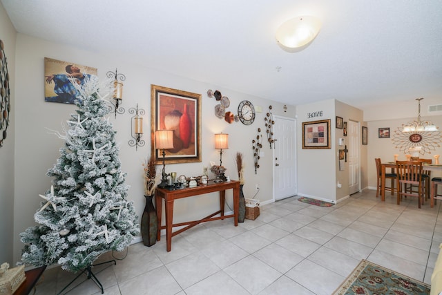 entryway featuring an inviting chandelier, light tile patterned floors, baseboards, and visible vents