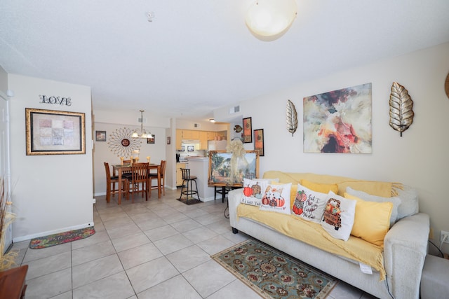 living area with an inviting chandelier, light tile patterned flooring, baseboards, and visible vents