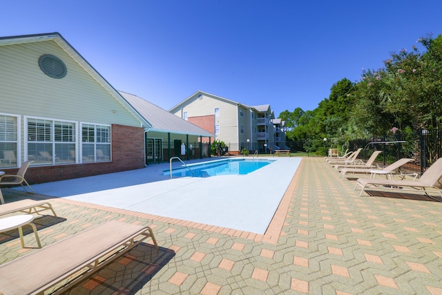 pool with a patio area and fence