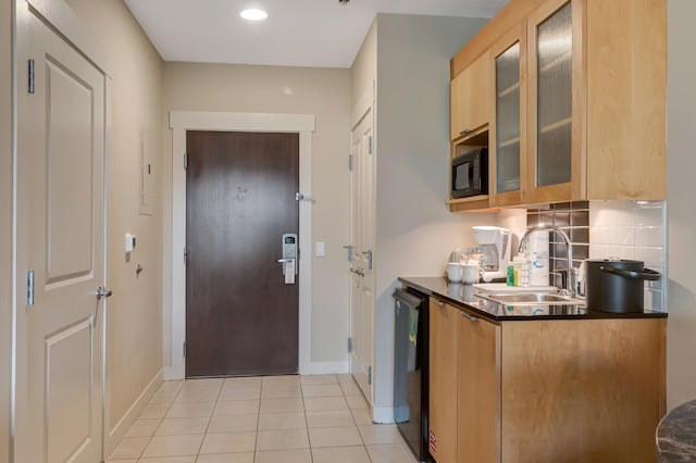 kitchen with dark countertops, light tile patterned floors, decorative backsplash, black appliances, and a sink