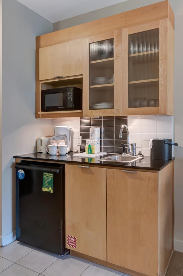 kitchen with fridge, tasteful backsplash, black microwave, and a sink