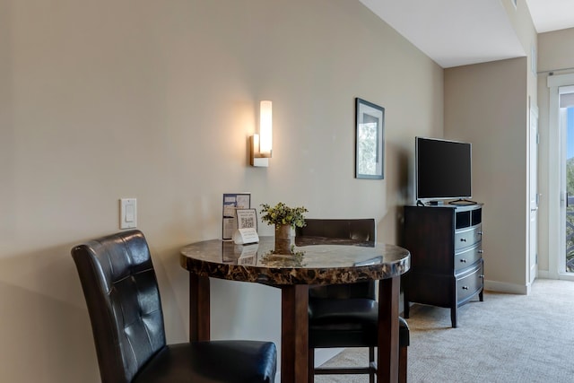 dining space featuring baseboards and light carpet