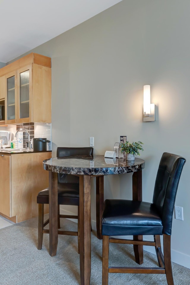 carpeted dining room with a sink and baseboards