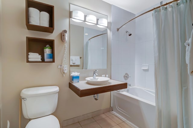 bathroom featuring tile patterned floors, toilet, shower / bath combo with shower curtain, and a sink