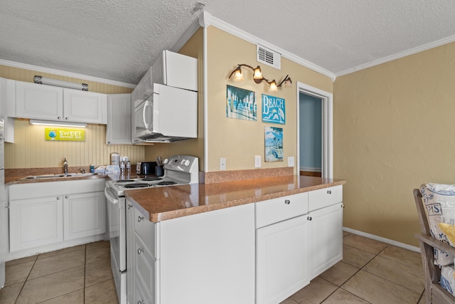 kitchen featuring white appliances, light tile patterned floors, a sink, white cabinets, and crown molding