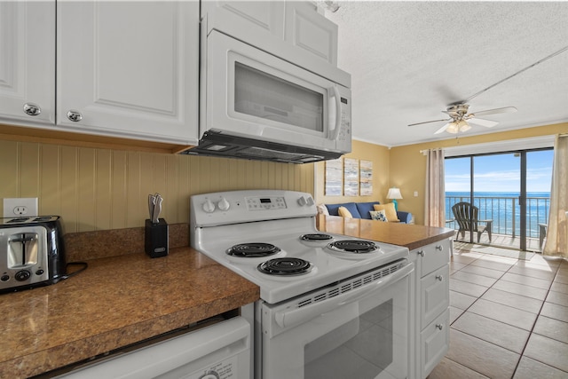 kitchen featuring white appliances, dark countertops, white cabinets, and a textured ceiling