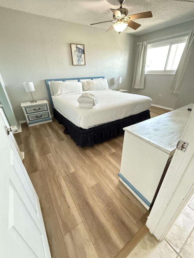 bedroom with a textured ceiling, ceiling fan, and wood finished floors