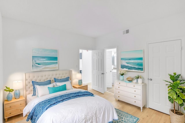 bedroom with visible vents, ensuite bath, and light wood finished floors