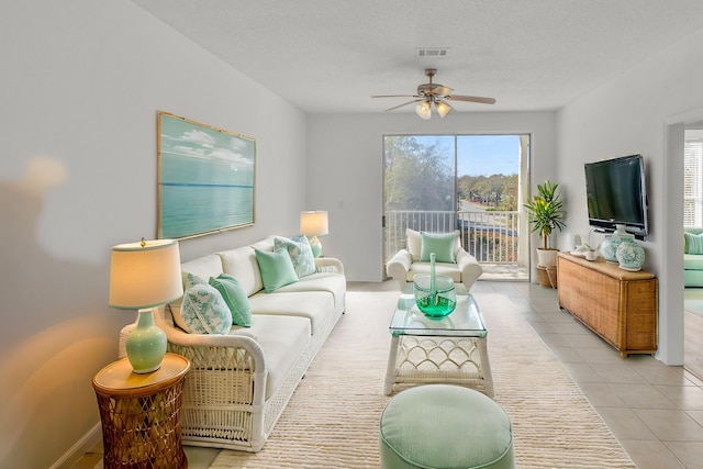 living room featuring visible vents, a ceiling fan, a textured ceiling, light tile patterned floors, and baseboards