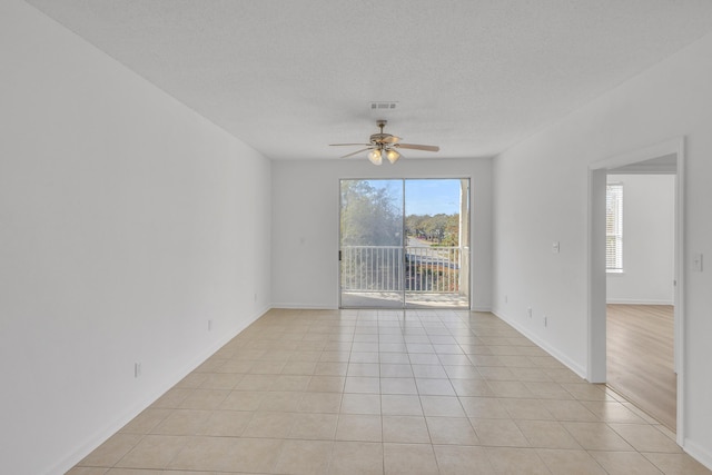 unfurnished room featuring visible vents, a textured ceiling, light tile patterned flooring, and a ceiling fan