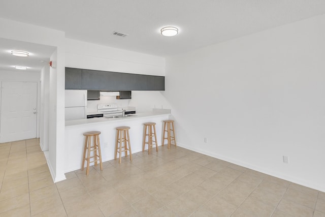 kitchen featuring white appliances, ventilation hood, a peninsula, light countertops, and a kitchen breakfast bar