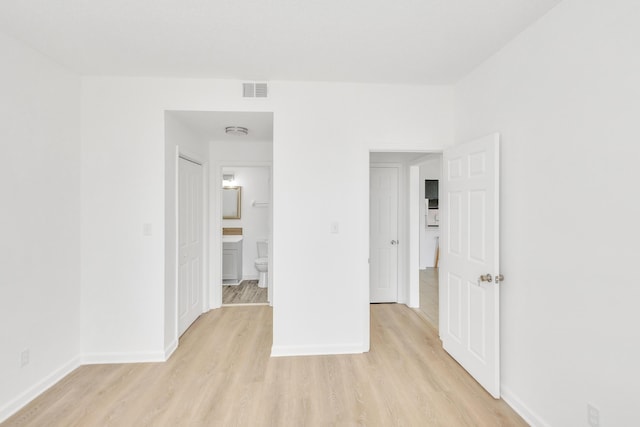 unfurnished room featuring visible vents, light wood-style flooring, and baseboards