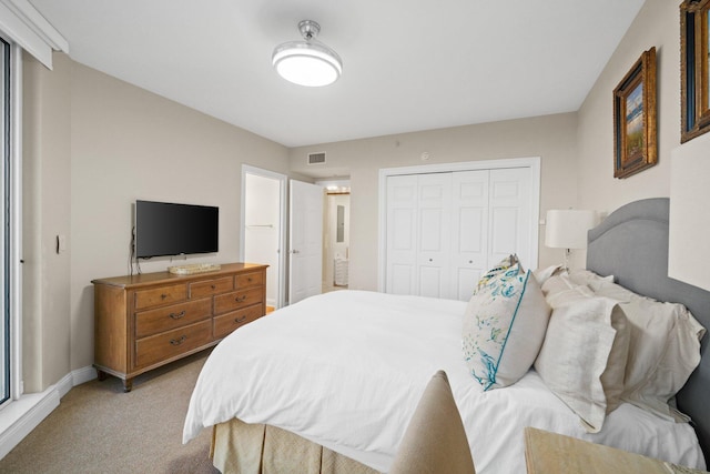 bedroom with visible vents, light carpet, a closet, connected bathroom, and baseboards