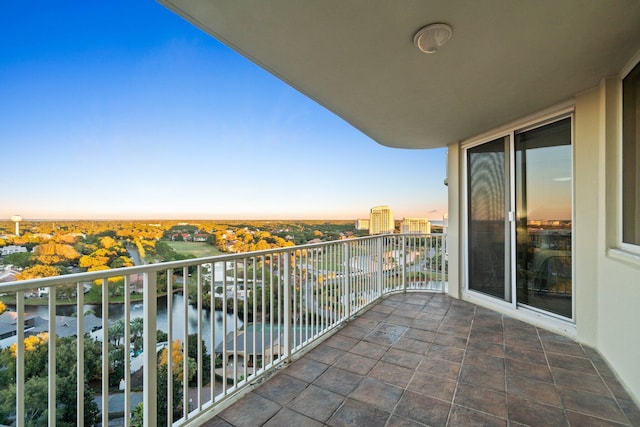 balcony at dusk featuring a city view and a water view