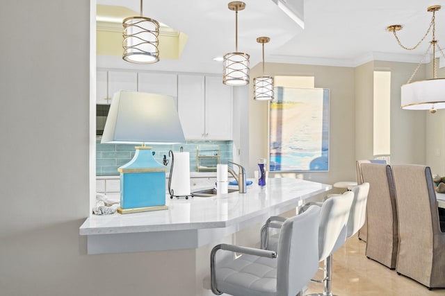 kitchen with hanging light fixtures, backsplash, crown molding, and a sink