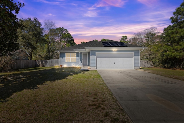 ranch-style house featuring fence, driveway, a front lawn, a garage, and roof mounted solar panels