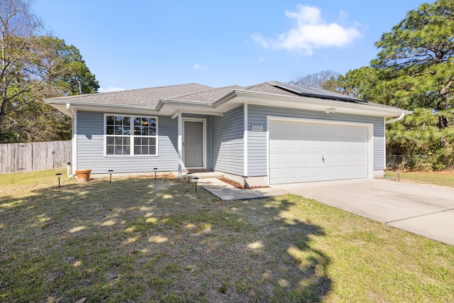 ranch-style house featuring a front lawn, fence, roof mounted solar panels, a garage, and driveway