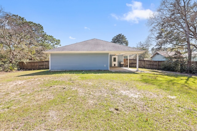 back of house featuring a patio area, a lawn, a fenced backyard, and a carport