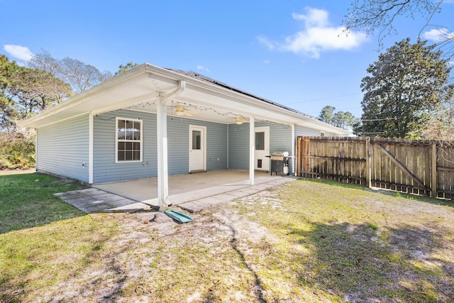 rear view of house featuring a patio, fence, and a lawn