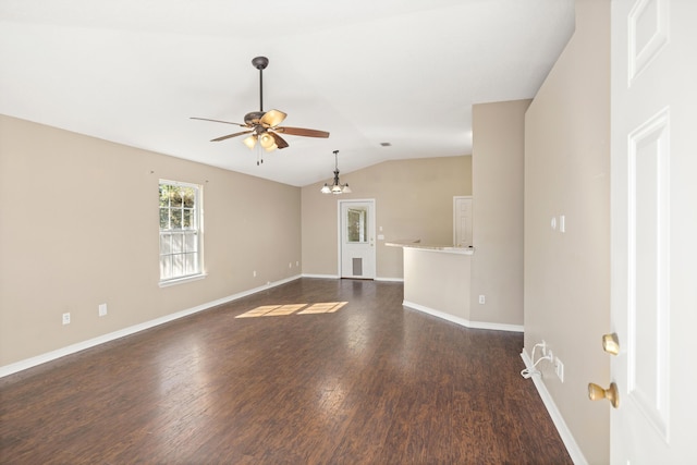 empty room featuring baseboards, ceiling fan with notable chandelier, dark wood finished floors, and vaulted ceiling