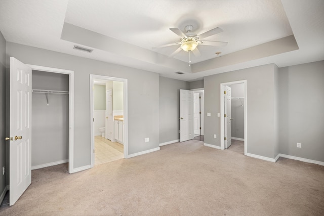 unfurnished bedroom featuring a tray ceiling, visible vents, a closet, and a spacious closet