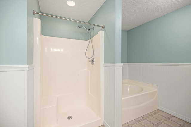 bathroom with tile patterned floors, a wainscoted wall, a textured ceiling, and a shower