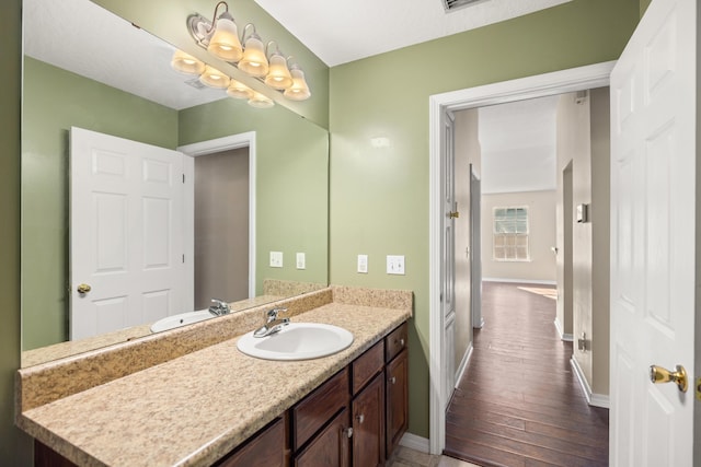 bathroom with vanity, visible vents, wood finished floors, and baseboards