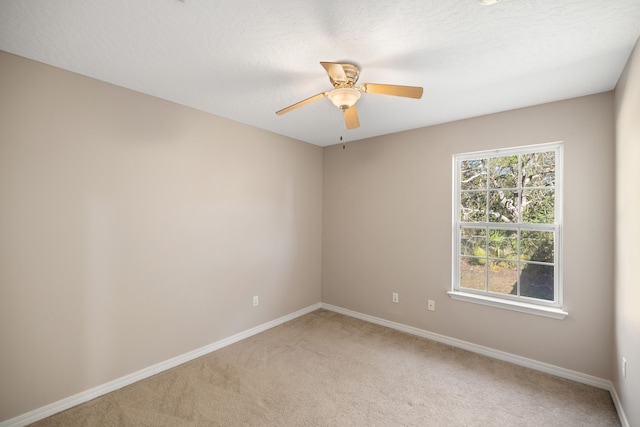 empty room with baseboards, a textured ceiling, light carpet, and ceiling fan