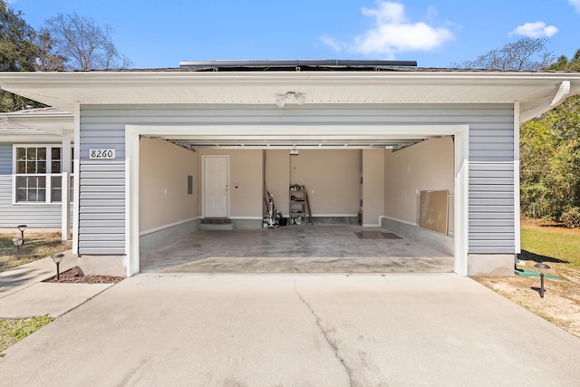 garage featuring concrete driveway and roof mounted solar panels