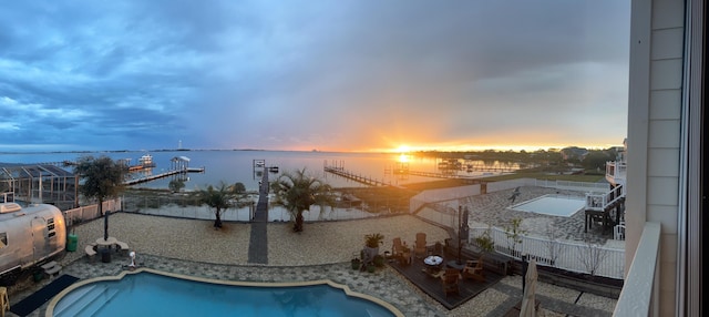 pool at dusk featuring a fenced in pool and a water view