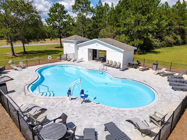 pool featuring a patio area, an outdoor structure, a yard, and fence